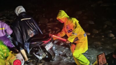 Menggunakan jas hujan dan penerangan seadanya, personel gabungan tetap bertugas membantu kelancaran arus lalu lintas di tengah cuaca ekstrem di Wih Porak. (Foto/dok, Ist*).