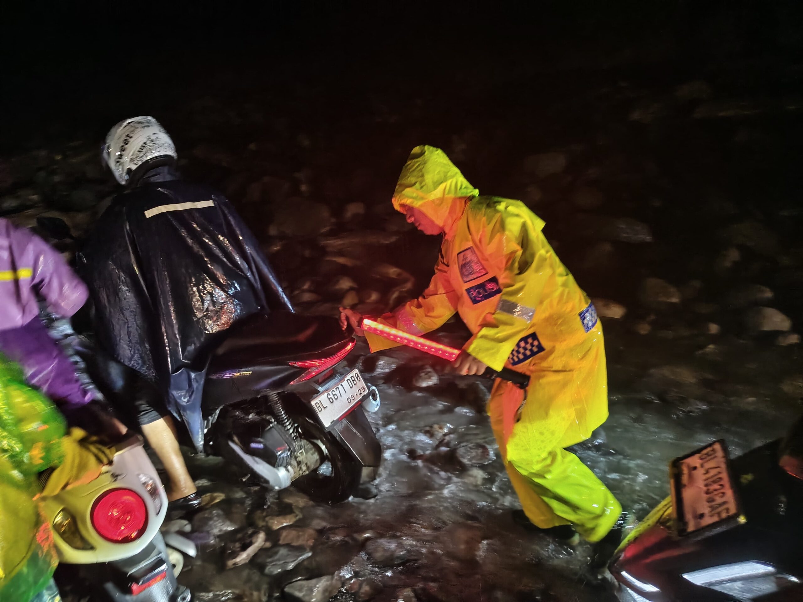 Menggunakan jas hujan dan penerangan seadanya, personel gabungan tetap bertugas membantu kelancaran arus lalu lintas di tengah cuaca ekstrem di Wih Porak. (Foto/dok, Ist*).