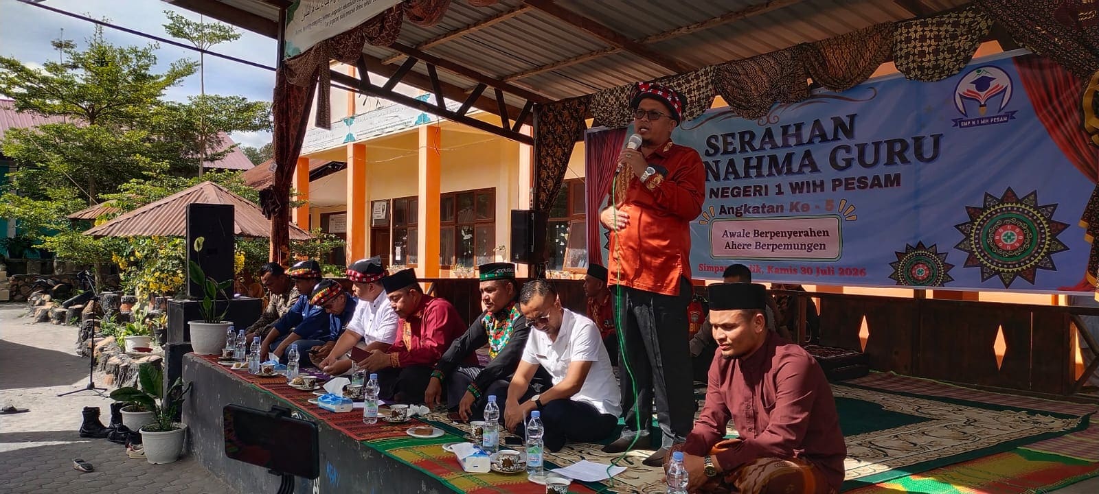 Suasana prosesi adat "I Serahan Ku Nahma Guru" yang digelar SMP Negeri 1 Wih Pesam, Kabupaten Bener Meriah, sebagai bentuk penghormatan kepada guru sekaligus upaya melestarikan adat dan budaya Gayo. Kegiatan ini dihadiri unsur pemerintah daerah, tokoh pendidikan, tokoh adat, Forkopimcam, komite sekolah, wali murid, alumni, serta para peserta didik.